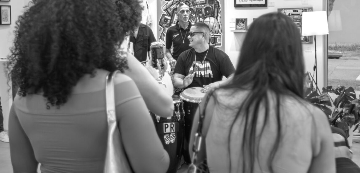 Documentary photograph from Sunset Rumba at WYN317 in Miami, showing live music and gallery activity during the closing reception for Carlos Solano’s exhibition “An Experience of Us.”